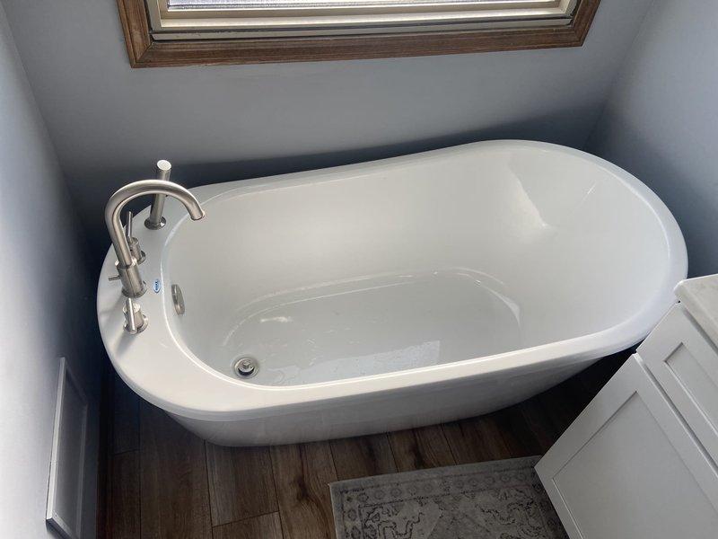 Successfully reinstalled customer's freestanding oval bathtub with brushed nickel fixtures following completion of new wood-look flooring installation. Properly connected water supply lines and drain assembly, then verified proper function with no leaks.