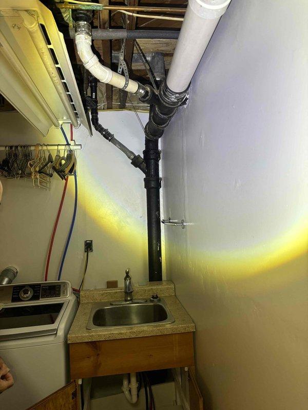 Responded to service call for clogged drain in laundry area. Inspected P-trap assembly and waste line connections beneath sink, noting mineral deposits around pipe fittings. Successfully cleared blockage in laundry sink drain and verified proper drainage function of the entire system.