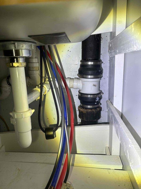 Responded to service call for clogged drain in laundry area. Inspected P-trap assembly and waste line connections beneath sink, noting mineral deposits around pipe fittings. Successfully cleared blockage in laundry sink drain and verified proper drainage function of the entire system.