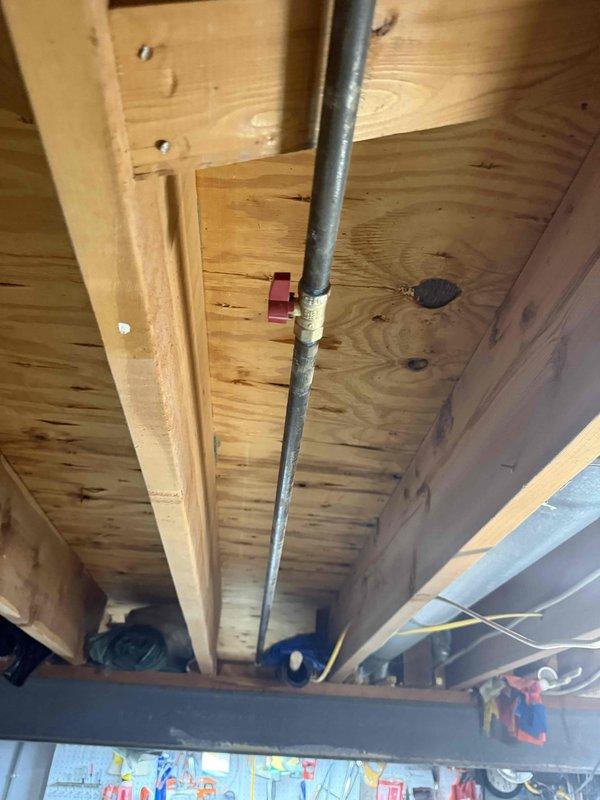 Performed comprehensive gas pressure test on basement gas line system that was previously serviced. Inspection of the galvanized steel piping installation revealed T-junction configurations with potential weak points at union joints. Documentation with photos captured the condition of pipe connections and mounting hardware, including the reddish bracket securing the gas line to wooden joists. No active leak was located during this service visit; system was left operational with recommendations for continued monitoring.