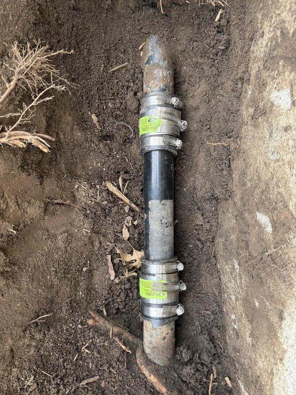 # Plumbing Service Report

Excavated and exposed underground sump pump discharge line buried approximately 1-2 feet below grade near building foundation. Removed damaged section of discharge piping and installed new pipe segment with flexible rubber couplings and stainless steel hose clamps to ensure secure, leak-free connections. Backfilled excavation area with soil, restored grade level, and performed operational testing to verify proper drainage flow through the repaired discharge line.