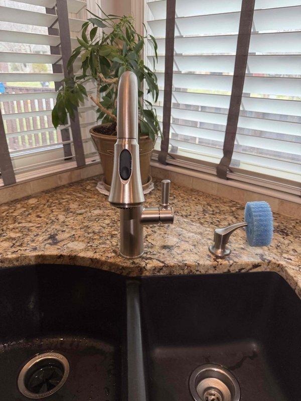 # Service Report: Kitchen Faucet Installation

Successfully installed customer-supplied kitchen faucet with integrated sprayer on double-basin composite sink with granite countertop. Installation included mounting the rose gold/copper-finish faucet assembly, connecting hot and cold water supply lines with braided stainless steel flex hoses, securing all mounting hardware through countertop, and verifying proper operation of both standard flow and pull-out sprayer functions. All connections tested and confirmed leak-free with no issues detected in the P-trap drainage system or under-sink plumbing configuration.