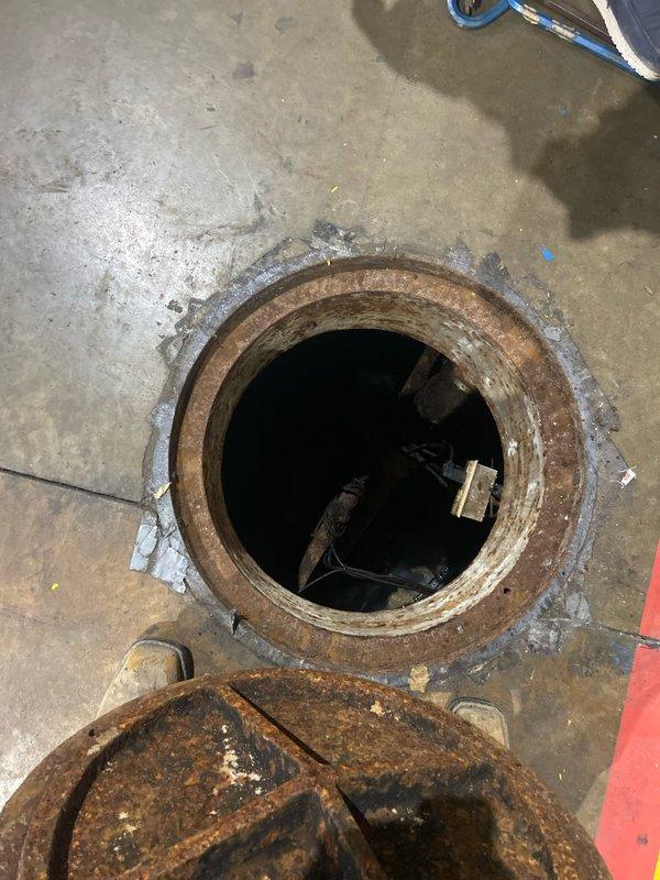 Conducted site assessment of grinder pump system accessed through floor-mounted access port in commercial facility. Evaluated existing pump conditions, documented corroded access ring and manhole cover, and provided detailed estimate for grinder pump replacement including associated components and installation requirements.