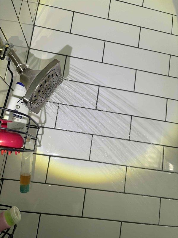 Completed comprehensive plumbing inspection of residential property. Examined utility room plumbing connections including PVC supply lines, chrome fittings, and braided supply hoses, confirming proper installation and secure connections. Inspected bathroom shower system including wall-mounted chrome showerhead fixture and water pressure performance, verifying adequate flow and spray pattern functionality with no visible leaks or drainage issues detected.