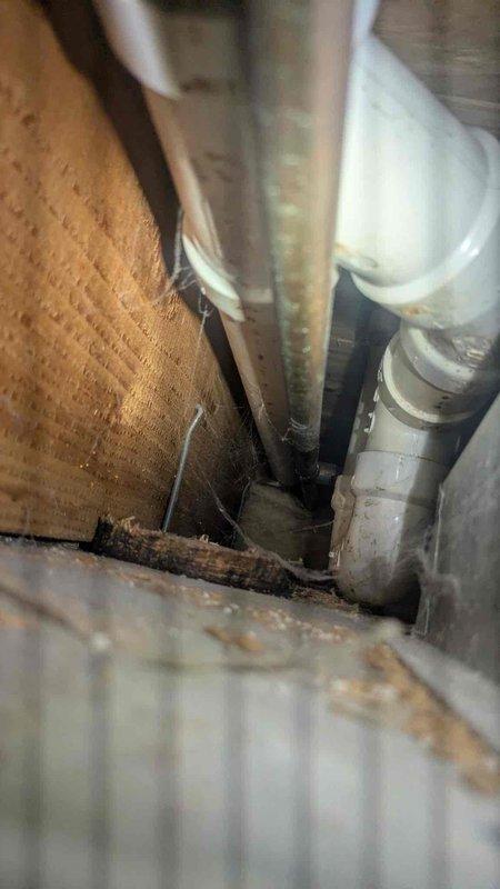 Responded to reported water leak occurring during washing machine operation. Upon arrival, conducted thorough inspection of plumbing system and identified source of water intrusion affecting ceiling and subfloor areas. 

Investigation revealed compromised drainage system with visible water damage to ceiling drywall and underlying structural components. Created access opening in ceiling to assess extent of damage and locate leak source. Inspection of crawlspace revealed deteriorated materials, moisture accumulation, and evidence of prolonged water exposure affecting wooden subfloor components and surrounding areas.

Traced leak to washing machine drain line connection. Found improper drainage causing water backup during wash cycles, resulting in overflow conditions that penetrated ceiling and floor structures. White PVC drainage piping showed signs of stress and improper installation contributing to the backup issue.

Documented existing conditions with photographs showing ceiling damag