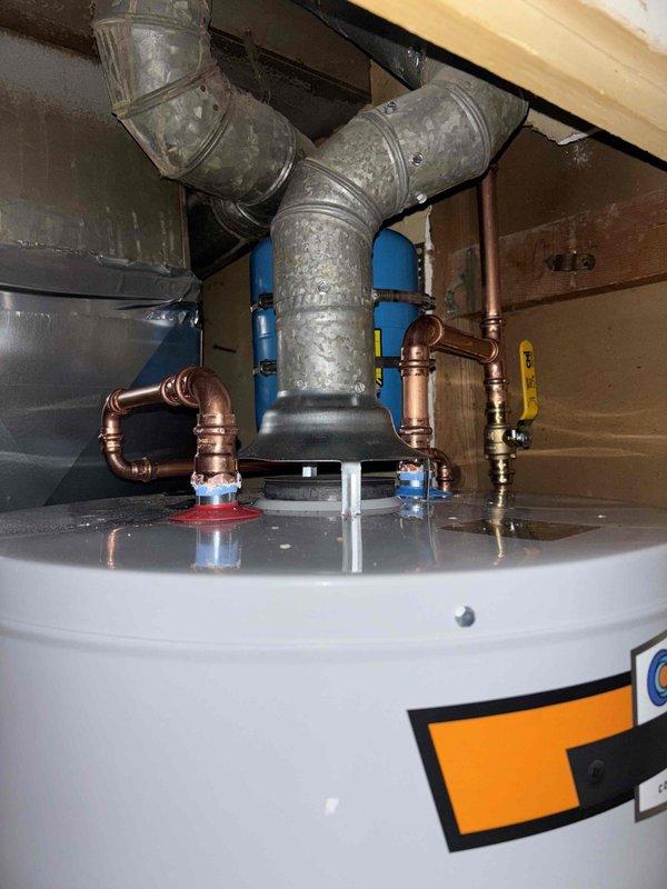 Completed installation of 40-gallon gas water heater with thermal expansion tank in residential utility space. Connected gas supply line using flexible yellow corrugated connector, installed proper venting ductwork, and made all necessary copper water line connections with shutoff valves. All safety labels verified in place, unit tested and operational.
