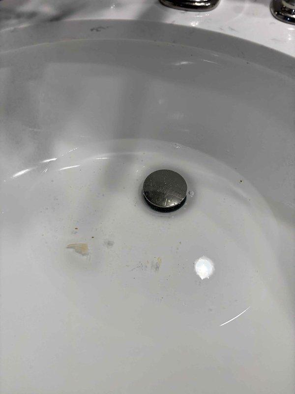 Responded to reported clogged drain with backup from upstairs kitchen sink to main bathroom sink downstairs. Upon inspection, confirmed water accumulation with residue in bathroom sink basin. Assessed drainage system and cleared blockage causing cross-contamination between fixtures. Verified proper drainage flow restored to both kitchen and bathroom sinks, eliminating backup issue.