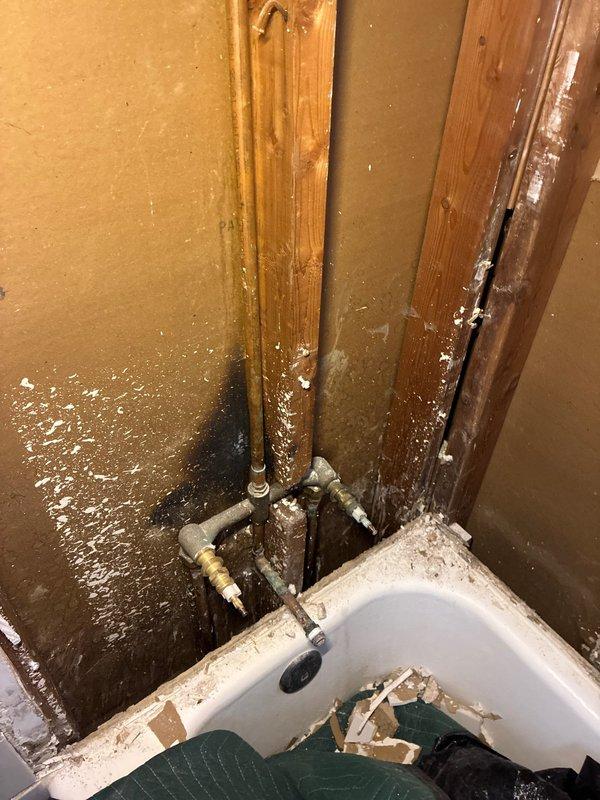 Responded to service call for shower piping replacement and cartridge installation. Upon arrival, found bathroom area with significant water damage, exposed framing, and deteriorated drywall requiring immediate attention. Assessed existing plumbing system with copper supply lines and connections visible in damaged wall cavity. Customer requested updated shower valve assembly and supply line installation to accommodate new cartridge-style fixture. Documented extensive water damage to flooring, wall panels, and door frame indicating previous or ongoing moisture intrusion. Evaluated plumbing rough-in and existing pipe configuration to determine scope of replacement work needed for proper cartridge valve installation.