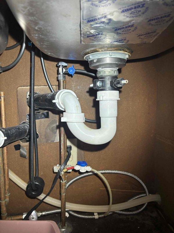 Completed comprehensive plumbing inspection of kitchen sink system and garbage disposal unit. All components including stainless steel sink drain assembly, chrome strainer basket, white PVC P-trap, flexible braided supply lines, shutoff valves, and garbage disposal with corrugated drain hose were examined and found to be properly installed and functioning within normal parameters.
