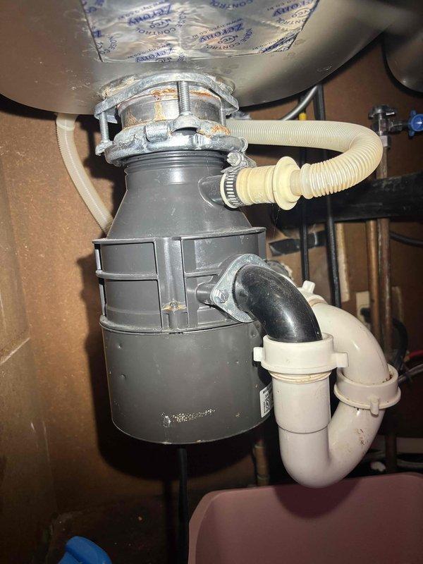 Completed comprehensive plumbing inspection of kitchen sink system and garbage disposal unit. All components including stainless steel sink drain assembly, chrome strainer basket, white PVC P-trap, flexible braided supply lines, shutoff valves, and garbage disposal with corrugated drain hose were examined and found to be properly installed and functioning within normal parameters.