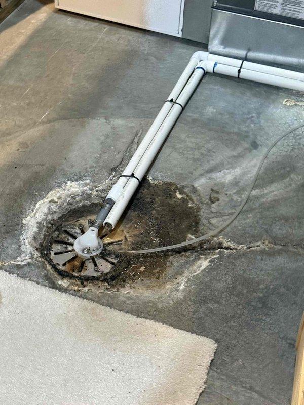 Responded to service call for tanked water heater with reported crust formation at top of unit, water pooling, and improper flue venting. Upon inspection in basement, confirmed mineral deposit buildup on top of water heater and evidence of condensation issues related to compromised venting system. Assessed flue pipe configuration and determined improper draft was causing combustion gases to condense, leading to corrosion and water accumulation. Performed diagnostic evaluation of venting components and water heater operation. Addressed drainage concerns and documented existing conditions showing water staining on floor around unit. Completed necessary repairs to restore proper venting function and resolve moisture infiltration issues.