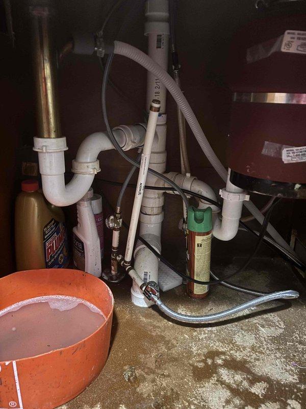 Responded to kitchen sink clog complaint and accessed cabinet area beneath sink to inspect drainage system. Upon examination, found P-trap assembly and associated PVC drain lines showing signs of blockage. Cleared obstruction from drain line, ensuring proper water flow through P-trap configuration and downstream piping. Tested system operation to verify drainage functioning correctly. Advised on proper sink usage to prevent future clogs.