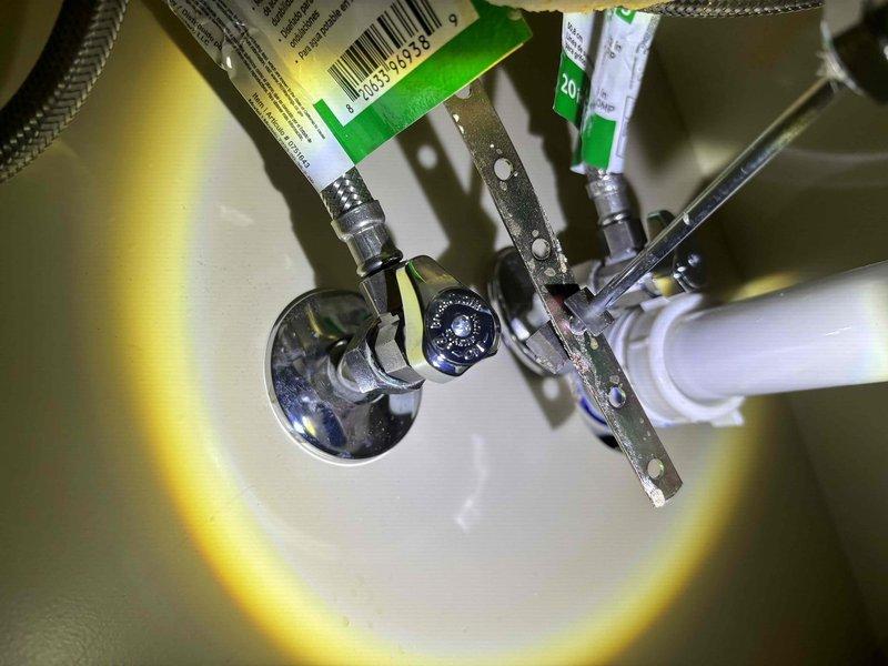 Responded to plumbing issue where hot water was leaking from the hot water knob when only the cold water valve was activated. Inspected under-sink plumbing components including flexible supply lines, shut-off valves, and connections to identify cross-connection or valve failure causing the anomaly. Documented existing plumbing configuration with supply lines, drain assembly, and valve hardware for diagnostic purposes and potential repair recommendation.