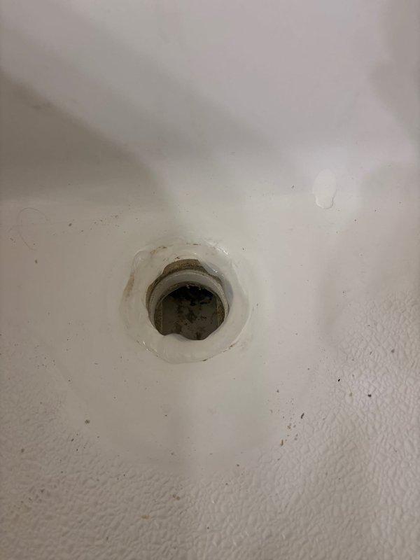 Responded to service call for replacement of two bathtub lift/lock drain plugs. Upon arrival, found that previous handyman attempt had resulted in damaged hardware, with the tool grab points broken off due to corrosion. Assessed the corroded drain assemblies and determined that standard removal tools could not engage the damaged fittings. Despite customer having replacement parts on hand, existing drain plugs could not be successfully extracted due to extensive corrosion and compromised hardware from prior removal attempt. Documented existing conditions showing significant rust staining and mineral deposits around drain openings in white porcelain fixtures.