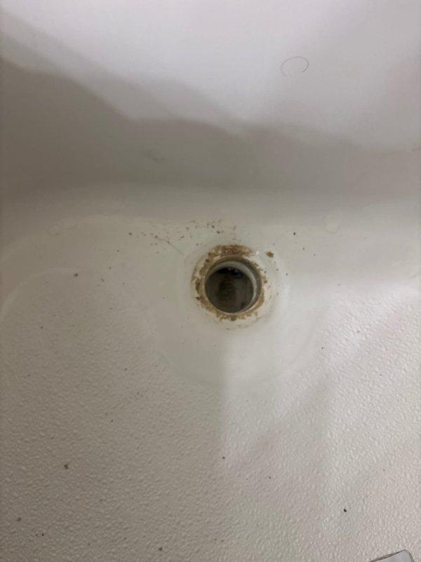 Responded to service call for replacement of two bathtub lift/lock drain plugs. Upon arrival, found that previous handyman attempt had resulted in damaged hardware, with the tool grab points broken off due to corrosion. Assessed the corroded drain assemblies and determined that standard removal tools could not engage the damaged fittings. Despite customer having replacement parts on hand, existing drain plugs could not be successfully extracted due to extensive corrosion and compromised hardware from prior removal attempt. Documented existing conditions showing significant rust staining and mineral deposits around drain openings in white porcelain fixtures.