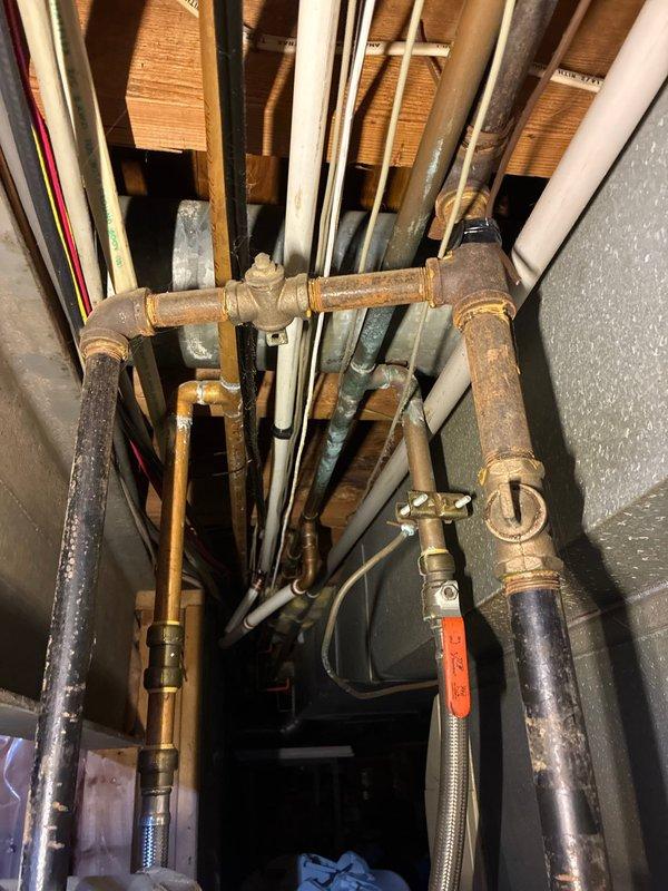 Conducted comprehensive assessment of 15+ year old tanked water heater system located in basement to provide replacement estimate. Inspected existing plumbing infrastructure, including supply lines, pressure relief valve, and associated copper piping, noting visible corrosion and oxidation on multiple metal pipes and fittings throughout the system. Documented current water pressure reading at approximately 80 psi using existing pressure gauge. Evaluated condition of all connections, including PVC drainage lines, flexible supply lines, and insulated pipes running through ceiling joists. Photographed existing installation configuration and equipment condition to support replacement recommendations for aging water heater unit.