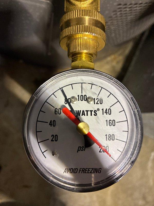 Conducted comprehensive assessment of 15+ year old tanked water heater system located in basement to provide replacement estimate. Inspected existing plumbing infrastructure, including supply lines, pressure relief valve, and associated copper piping, noting visible corrosion and oxidation on multiple metal pipes and fittings throughout the system. Documented current water pressure reading at approximately 80 psi using existing pressure gauge. Evaluated condition of all connections, including PVC drainage lines, flexible supply lines, and insulated pipes running through ceiling joists. Photographed existing installation configuration and equipment condition to support replacement recommendations for aging water heater unit.