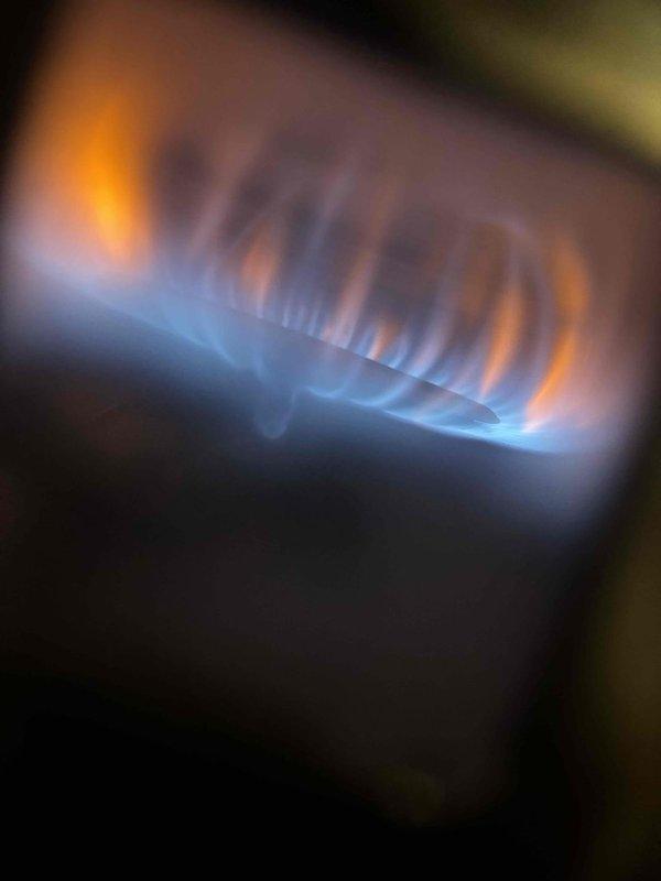 Responded to no-hot-water call for GE tanked water heater located in basement mechanical room. Upon arrival, performed visual inspection and diagnostic testing of unit. Found gas supply intact and pilot light assembly functioning properly. Verified burner ignition sequence and observed proper flame pattern with characteristic blue flames at base indicating efficient combustion. Checked thermocouple operation and gas valve functionality. Restored unit to full operational status with burner firing correctly in circular pattern. Verified adequate draft and proper venting. Unit tested and confirmed producing hot water at appropriate temperature settings.