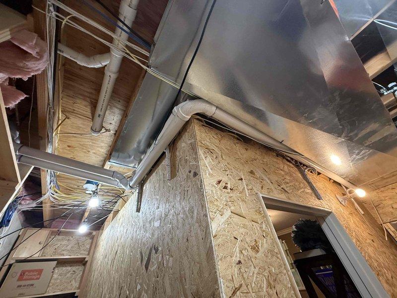 Removed and disposed of existing State brand tank-style water heater showing significant rust corrosion at top connections. Installed Rinnai RXP199 condensing tankless water heater with 96% efficiency rating and 11.00 GPM capacity in utility area. Ran approximately 15 feet of hot and cold Aquapex waterlines from main supply to new unit location. Installed gas supply line using black iron pipe with required tee fittings and two 90-degree elbows, including gas dirt leg and emergency shut-off valve per code requirements. Installed 2-inch PVC venting system for exhaust and fresh air intake, terminating appropriately for optimal unit operation and combustion air requirements. Capped existing gas lines and venting from previous water heater installation. Ran condensate drain line to floor drain with proper air vent installed below unit to prevent trap siphoning. Installed Rinnai-provided check valve on cold water line to enable hot water recirculation system, allowing hot water to return thr