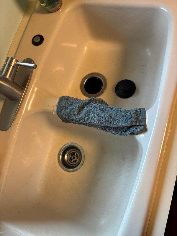 Responded to clogged kitchen sink in 67-year-old residential property. Upon arrival, assessed double basin porcelain sink with modern brushed stainless steel faucet and confirmed drainage obstruction. Accessed plumbing system beneath sink via cabinet storage area to diagnose blockage location. Utilized professional drain cleaning equipment and tools to clear obstruction from drain line. Verified proper water flow and drainage functionality upon completion. Restored work area to original condition.