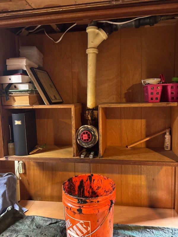 Responded to clogged kitchen sink in 67-year-old residential property. Upon arrival, assessed double basin porcelain sink with modern brushed stainless steel faucet and confirmed drainage obstruction. Accessed plumbing system beneath sink via cabinet storage area to diagnose blockage location. Utilized professional drain cleaning equipment and tools to clear obstruction from drain line. Verified proper water flow and drainage functionality upon completion. Restored work area to original condition.