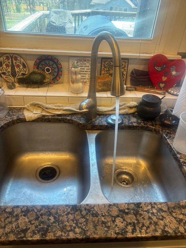 Responded to kitchen sink clog with garbage disposal unit. Upon arrival, assessed double-basin stainless steel sink installation and identified drainage obstruction in basin equipped with disposal. Cleared blockage from disposal unit and drain line, restoring proper water flow and drainage function. Tested both basins under running water to verify complete clearance and confirmed disposal operation. System returned to normal working condition with no further drainage issues observed.
