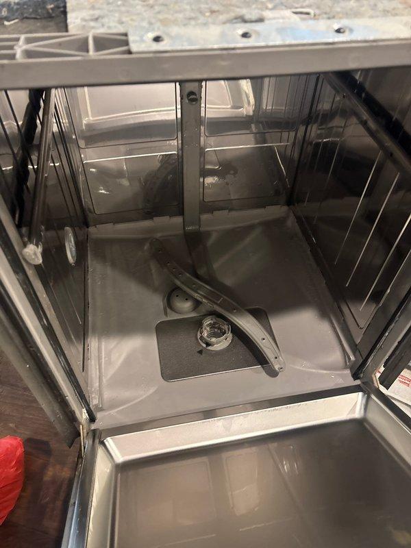 Responded to emergency leak detection call where water supply had been shut off due to active leak from dishwasher penetrating through kitchen floor into basement below. Performed visual inspection of dishwasher water supply connections, including braided stainless steel flex line and brass shut-off valve, as well as drain hose assembly with corrugated white flexible tubing and gray plastic fittings. Examined dishwasher interior chamber, spray arm assembly, and mounting components to identify source of water intrusion causing basement damage.