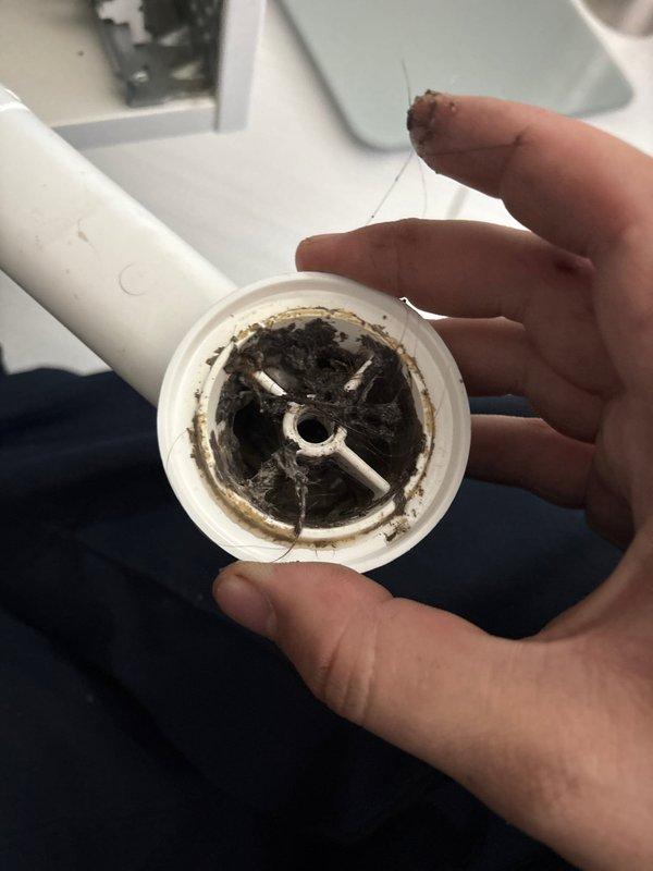 Responded to kitchen sink backup issue occurring during dishwasher operation. Upon inspection, identified significant debris and buildup accumulation in the drain assembly causing restricted water flow. Removed and cleaned the drain strainer, which exhibited heavy grime, tarnishing, and organic matter buildup on the metal cross-strainer mechanism. Cleared the drain line using appropriate tools to restore proper drainage capacity. Tested the system by running the dishwasher to verify water flows freely without backup. Drainage issue resolved successfully.