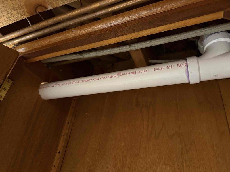 Redirected kitchen drain line in crawl space per approved specifications. Installed new white PVC drainage piping with proper fittings including T-junction connections to accommodate revised drain routing. All joints were properly primed and cemented following plumbing code requirements. New drainage configuration successfully diverts kitchen waste line to meet updated sewer lateral connection point.