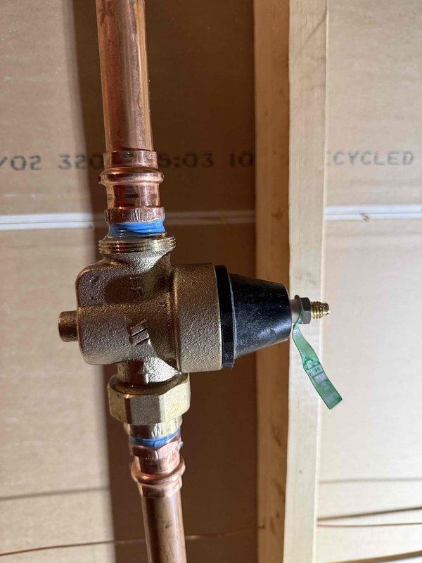 Installed a 3/4" pressure reducing valve (PRV) on the main water line, mounting the brass valve assembly with actuator between copper pipes using proper soldering techniques and securing connections with blue thread seal tape. Inspected bathroom sink faucet and identified leaking around hot and cold water handles requiring repair, and examined toilet to confirm broken flapper needing replacement.