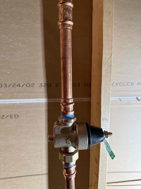 Installed a 3/4" pressure reducing valve (PRV) on the main water line, mounting the brass valve assembly with actuator between copper pipes using proper soldering techniques and securing connections with blue thread seal tape. Inspected bathroom sink faucet and identified leaking around hot and cold water handles requiring repair, and examined toilet to confirm broken flapper needing replacement.