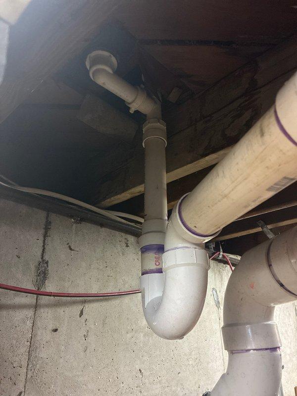 Completed a full repipe of main floor bathroom drainage system, removing deteriorated cast iron and galvanized piping. Removed toilet from flange and cut out cast iron back to the wye fitting at foundation wall. Carefully extracted cast iron from the hub while preserving the existing wye connection cast into the foundation. Installed a fernco hub adapter to transition from cast iron to PVC at the hub connection. Ran new PVC drainage piping to service the vent stack, bathtub drain, lavatory drain, and installed new toilet flange. Reinstalled the original toilet onto the new flange. Conducted comprehensive leak testing on all fixtures with water flow to verify integrity of new pipe runs. Removed all construction debris and materials from the workspace upon completion.