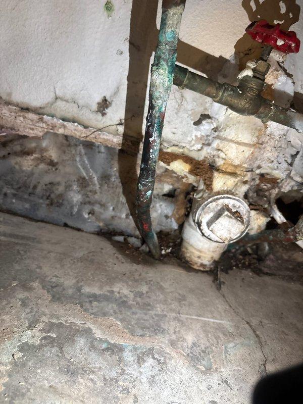 Responded to reported water leak in kitchen area during scheduled business hours. Upon arrival, conducted thorough diagnostic inspection of the plumbing system to identify the source of the leak. Investigation revealed deteriorated copper water supply lines in the basement utility area beneath the kitchen, exhibiting significant corrosion and green patina buildup indicative of prolonged moisture exposure and copper oxidation.

Inspection documented extensive water damage to surrounding concrete surfaces, walls, and flooring, with visible staining patterns confirming active leakage from the compromised piping. The affected copper lines showed advanced deterioration requiring immediate attention to prevent further water damage and potential flooding. Additional assessment of the plumbing infrastructure revealed aging components throughout the system, including corroded pipe sections and compromised connections near the water heater installation area.

Completed diagnostic evaluation and 