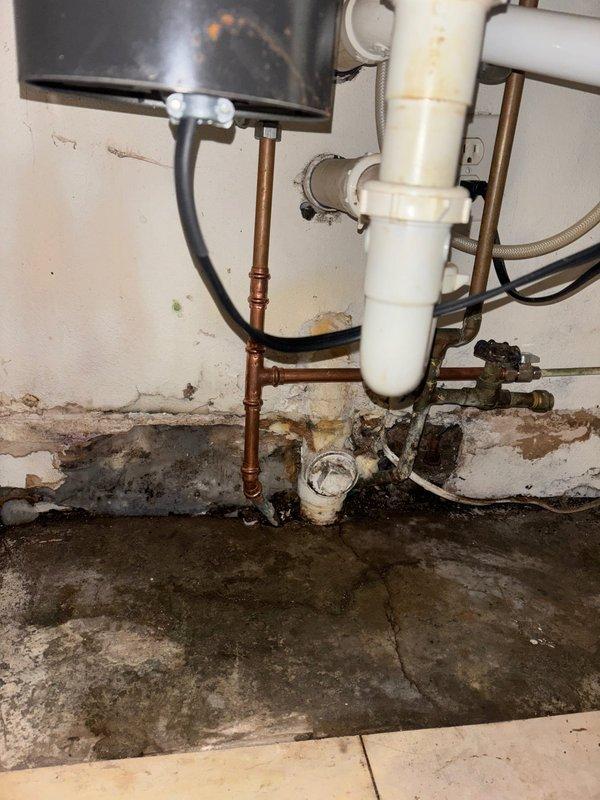 Responded to reported water leak in kitchen area during scheduled business hours. Upon arrival, conducted thorough diagnostic inspection of the plumbing system to identify the source of the leak. Investigation revealed deteriorated copper water supply lines in the basement utility area beneath the kitchen, exhibiting significant corrosion and green patina buildup indicative of prolonged moisture exposure and copper oxidation.

Inspection documented extensive water damage to surrounding concrete surfaces, walls, and flooring, with visible staining patterns confirming active leakage from the compromised piping. The affected copper lines showed advanced deterioration requiring immediate attention to prevent further water damage and potential flooding. Additional assessment of the plumbing infrastructure revealed aging components throughout the system, including corroded pipe sections and compromised connections near the water heater installation area.

Completed diagnostic evaluation and 