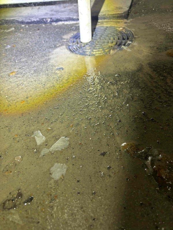 Responded to after-hours call for basement drainage issue where homeowner was uncertain whether sump pump or drain system was malfunctioning. Upon inspection, found existing sump pump with suspended discharge pipe configuration secured by chain mounting system. Observed significant standing water accumulation on basement floor surrounding PVC discharge pipe, with visible water pooling and ripple patterns indicating active drainage problems. Concrete floor exhibited extensive yellow and brown staining consistent with chronic moisture infiltration and mineral deposits from prolonged water exposure. Assessed mechanical components including pump discharge assembly and drainage infrastructure. Documented conditions showing compromised water management system requiring repairs to restore proper functionality and prevent continued basement flooding.