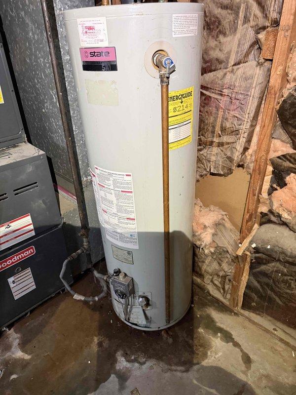Performed comprehensive assessment of 10-year-old State brand water heater located in basement utility area showing active leak conditions. Unit was still operational but exhibited water damage evidence on concrete floor beneath tank, indicating compromised tank integrity requiring replacement. Evaluated existing copper supply line connections, shut-off valves, and discharge piping configuration to determine replacement specifications and compatibility requirements for new water heater installation.
