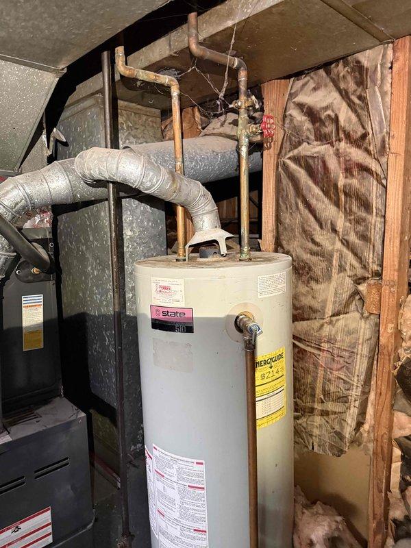 Performed comprehensive assessment of 10-year-old State brand water heater located in basement utility area showing active leak conditions. Unit was still operational but exhibited water damage evidence on concrete floor beneath tank, indicating compromised tank integrity requiring replacement. Evaluated existing copper supply line connections, shut-off valves, and discharge piping configuration to determine replacement specifications and compatibility requirements for new water heater installation.