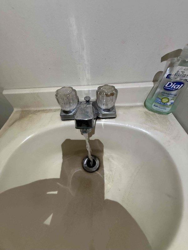 Performed recurring plumbing maintenance service including floor drain inspection and cleaning to remove debris buildup and sediment accumulation. Verified proper water flow and drainage functionality at bathroom sink fixture with chrome faucet assembly.