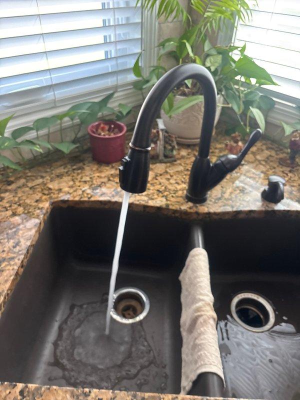 Completed comprehensive plumbing inspection of residential property. Examined bathroom toilet installation, verifying proper water supply line connections, shut-off valve operation, and braided metal supply line integrity. Inspected kitchen plumbing system including double-basin composite sink, pull-down faucet assembly, drain functionality, and water flow performance. All fixtures photographed and documented for reference.