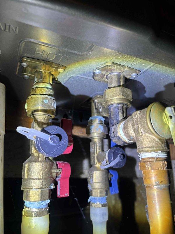 Completed annual plumbing maintenance inspection on Rinnai tankless water heater system. Inspected all service shutoff valves, ball valves, and plumbing connections beneath unit for proper operation and signs of leaks. Verified pressure relief valve functionality, checked brass fittings and compression connections for integrity, and confirmed all hot and cold water supply lines were secure with no visible corrosion or deterioration.