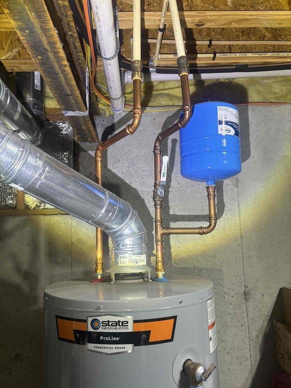 Responded to reported water heater leak in basement. Upon inspection, found State brand tanked water heater with active leak requiring replacement. Removed old leaking unit and installed new State water heater with proper copper supply line connections and brass fittings. Installed blue expansion tank on hot water outlet line to protect system from thermal expansion. Applied thread seal tape to all threaded connections to ensure leak-free operation. Secured all copper piping with appropriate supports and verified proper clearances. Tested system for leaks, confirmed adequate water pressure, and ensured proper temperature settings. All connections sealed and operational upon completion.