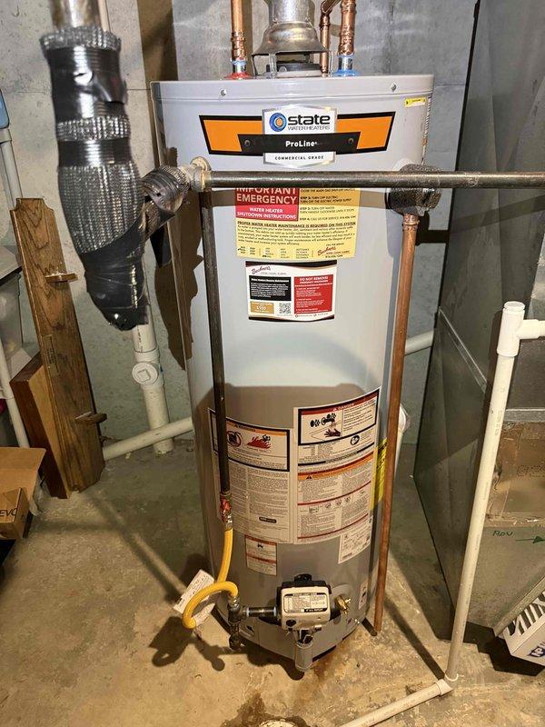 Successfully installed a 50-gallon State ProLine commercial-grade gas water heater with thermal expansion tank in the basement utility room. All copper supply line connections were completed at the top of the unit with appropriate shut-off valves, and the yellow flexible gas line was properly connected to the gas control valve assembly at the base. The installation includes all required safety labels, proper venting, and the unit was tested for proper operation upon completion.