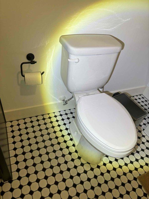 Completed plumbing maintenance inspection under bathroom sink and toilet area. Verified proper installation and functionality of white PVC P-trap assembly with threaded couplings, chrome sink drain basket connection, and dual chrome braided water supply lines with wall-mounted escutcheon plates. All plumbing components showed no signs of leaks, corrosion, or wear, confirming system integrity.
