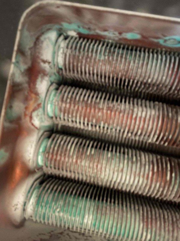 Performed comprehensive maintenance on a Rinnai RH-180 tankless water heater involving complete disassembly and manual cleaning of the heat exchanger assembly. The heat exchanger exhibited significant corrosion and oxidation buildup on the copper coil tubes and surrounding metallic components, with visible green patina indicating prolonged exposure to moisture and mineral deposits. Removed all four parallel cylindrical tubes from the housing, thoroughly cleaned the spiral fins and connecting points to remove accumulated scale and corrosion, then reassembled the unit to restore optimal heat transfer efficiency and extend equipment lifespan.