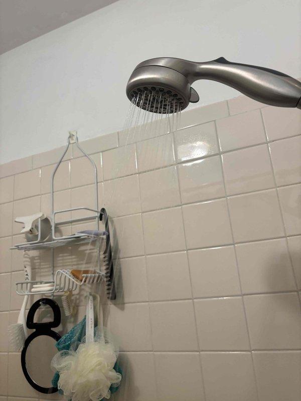 Completed preventative plumbing maintenance inspection on residential property. Verified proper operation of bathroom shower fixture with handheld showerhead, confirmed adequate water flow and spray pattern, and inspected plumbing connections behind access panel. Examined mechanical system components including filter assembly, refrigerant lines with brass fittings, and associated ductwork insulation for signs of leaks or deterioration. All fixtures and connections found to be functioning within normal parameters with no immediate repairs required.