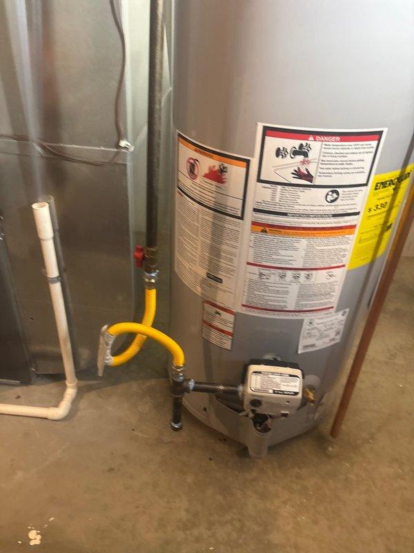 Installed 50-gallon STATE gas water heater with thermal expansion tank and ball valve shut-off on water inlet line. Removed and disposed of two existing water heaters from the property. Re-piped flue venting system to accommodate single water heater configuration and removed excess gas supply line that previously served secondary unit. Installed humidifier shut-off valve integrated with water heater system. Connected yellow flexible gas line to unit with proper fittings and routed copper supply and discharge piping with soldered connections. Mounted blue thermal expansion tank to system per code requirements. All connections tested and verified operational. Installation includes one-year labor warranty and six-year manufacturer warranty coverage.