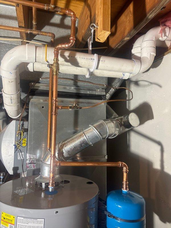 Installed 50-gallon STATE gas water heater with thermal expansion tank and ball valve shut-off on water inlet line. Removed and disposed of two existing water heaters from the property. Re-piped flue venting system to accommodate single water heater configuration and removed excess gas supply line that previously served secondary unit. Installed humidifier shut-off valve integrated with water heater system. Connected yellow flexible gas line to unit with proper fittings and routed copper supply and discharge piping with soldered connections. Mounted blue thermal expansion tank to system per code requirements. All connections tested and verified operational. Installation includes one-year labor warranty and six-year manufacturer warranty coverage.