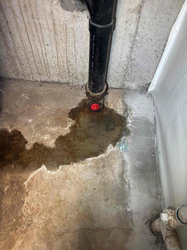 Responded to a sewer line backup in the basement. Upon arrival, found significant water damage and staining on the concrete floor radiating from the main drain cleanout pipe, with evidence of recent sewage overflow. Deployed professional drain cleaning equipment and performed mechanical augering of the main sewer line through the basement cleanout access point. Successfully cleared the blockage and restored proper drainage flow. Set up air circulation equipment to assist with drying the affected floor area following the water intrusion.