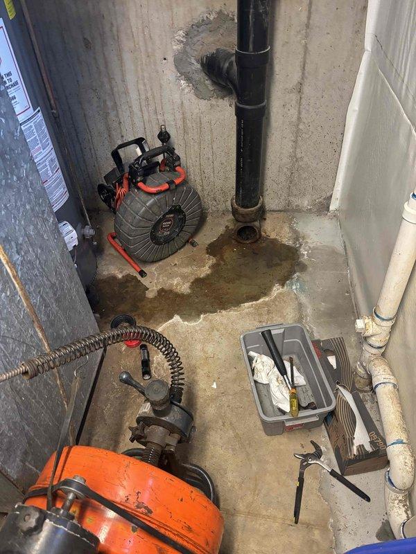 Responded to a sewer line backup in the basement. Upon arrival, found significant water damage and staining on the concrete floor radiating from the main drain cleanout pipe, with evidence of recent sewage overflow. Deployed professional drain cleaning equipment and performed mechanical augering of the main sewer line through the basement cleanout access point. Successfully cleared the blockage and restored proper drainage flow. Set up air circulation equipment to assist with drying the affected floor area following the water intrusion.