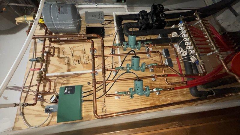 Replaced two circulator pumps in the hydronic heating system and installed new service ports to facilitate future maintenance access. Replaced the air separator head assembly and reconnected all copper piping with proper fittings and support brackets. The installation includes a manifold distribution system with zone control valves, integrated electrical controls, and insulated piping connections to the existing ductwork infrastructure.